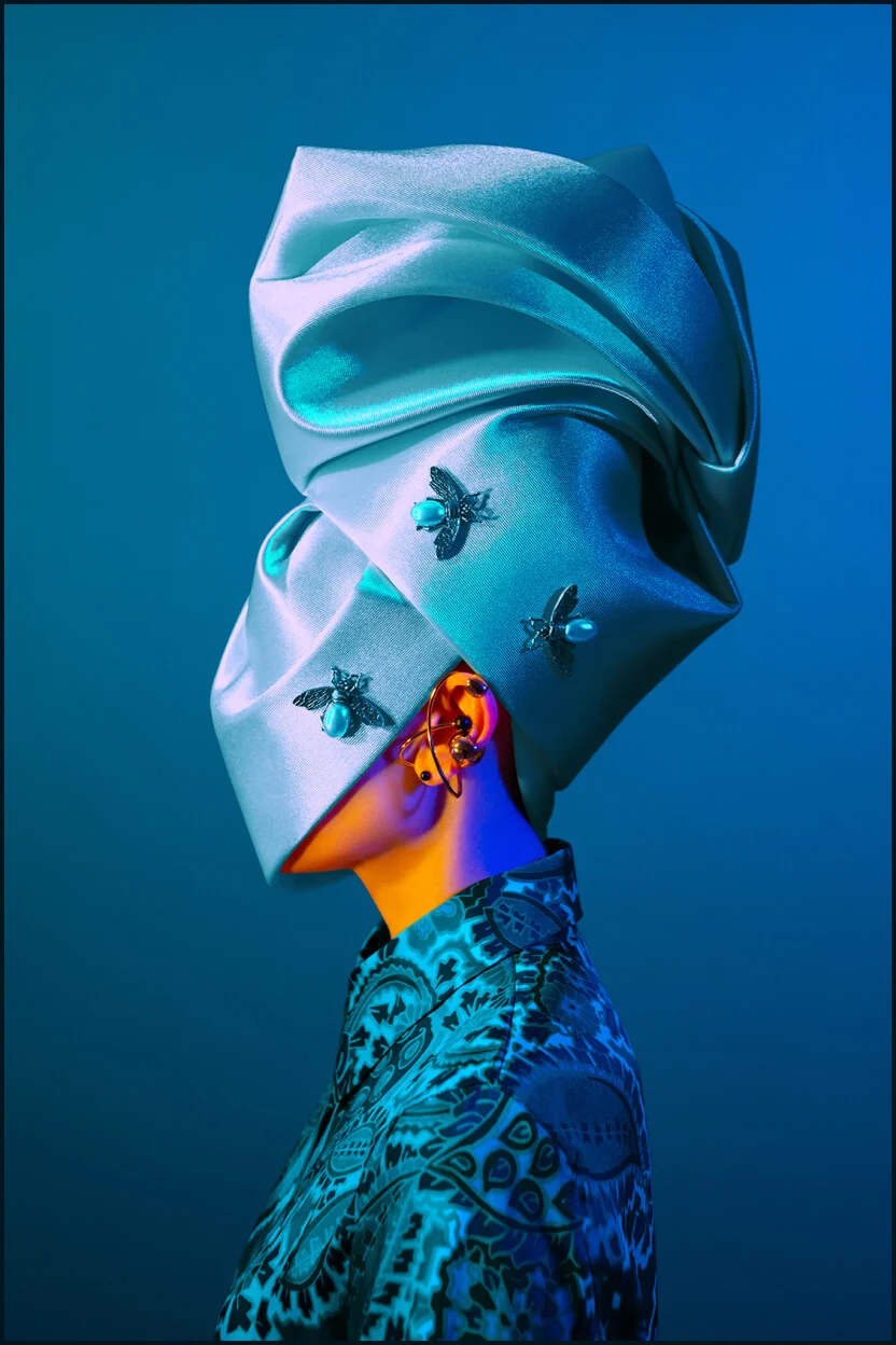 Metamorphoses Envoy portrait with a blue sculptural headpiece and insect jewellery