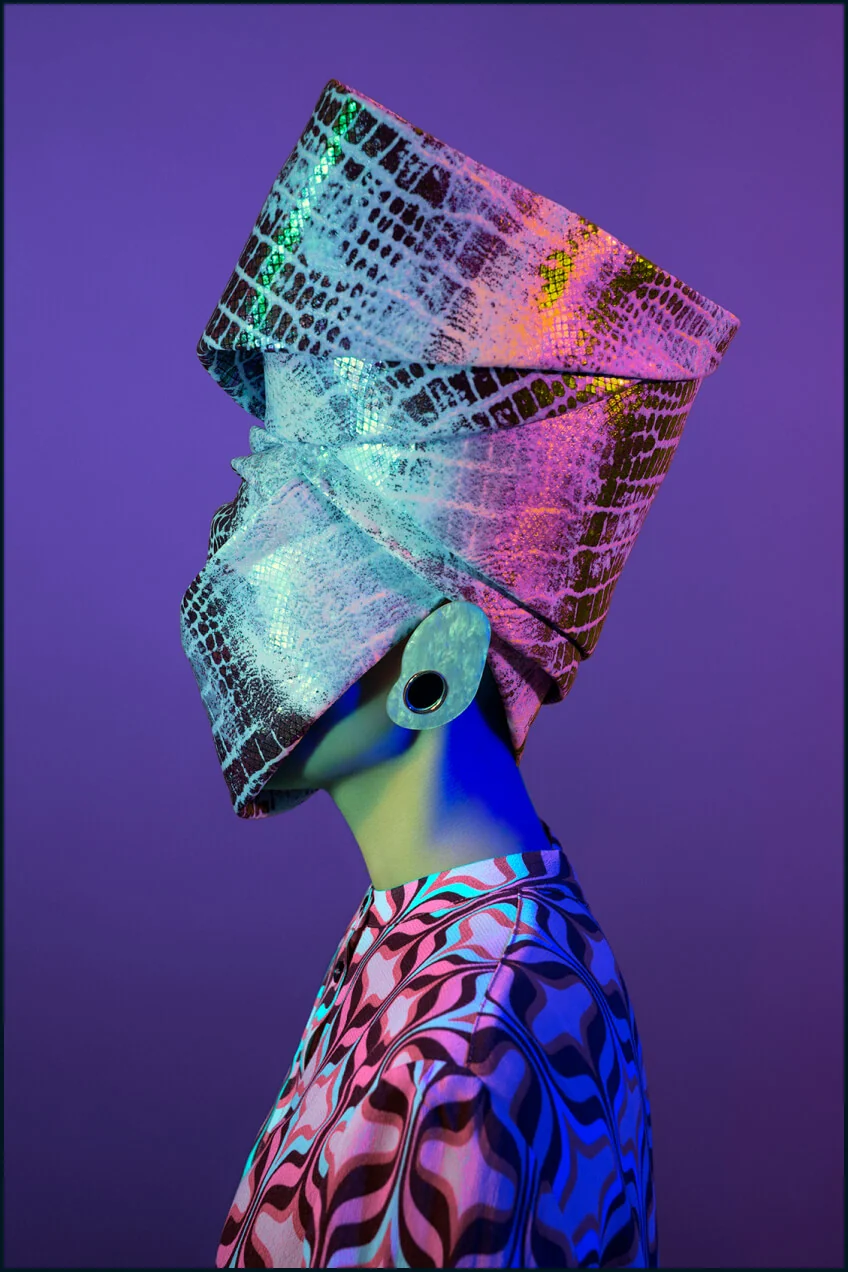 Metamorphoses Envoy portrait with a sculptural purple headpiece and multicolour light
